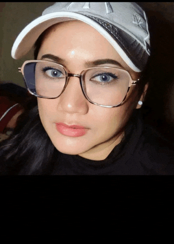 a woman wearing glasses and a baseball cap with the letter a on it