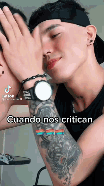 a man with a tattoo on his arm is covering his face with his hands