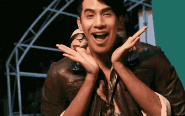 a man in a leather jacket is making a funny face with his hands