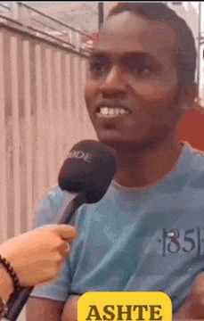 a man in a blue shirt is being interviewed by a person with a microphone .