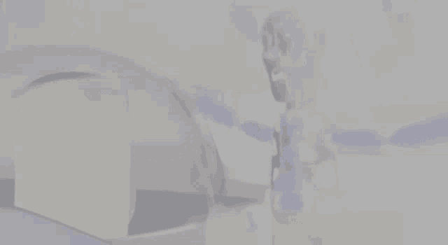 a blurred image of a person standing in front of a white wall
