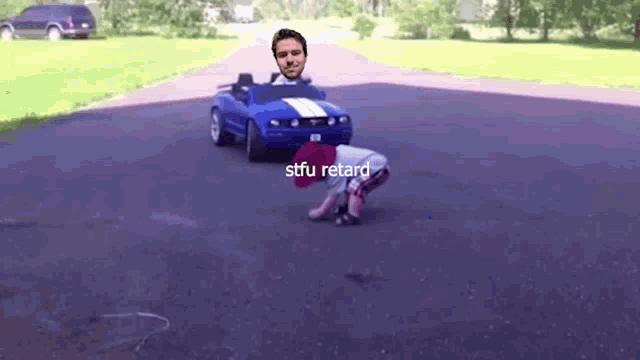 a little boy is crawling in front of a toy car that says stfu retard