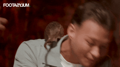 a mouse is sitting on a man 's neck and the words foota2ylum are visible in the background