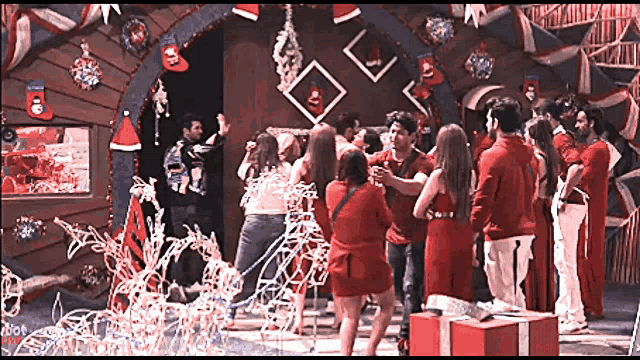 a group of people dressed in red are standing in front of a christmas decoration