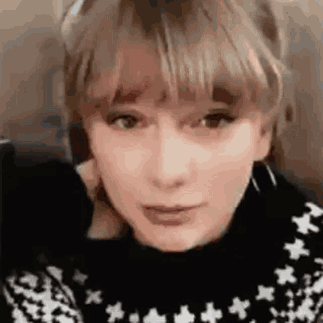a close up of a woman 's face wearing a black and white sweater with stars on it .