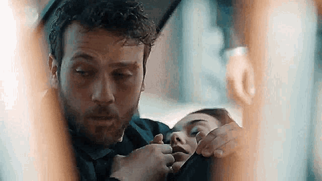 a man is holding a woman 's hand while she lays on his lap .