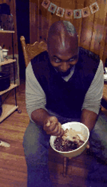 a man sitting in a chair eating a bowl of food with a banner behind him that says happy birthday