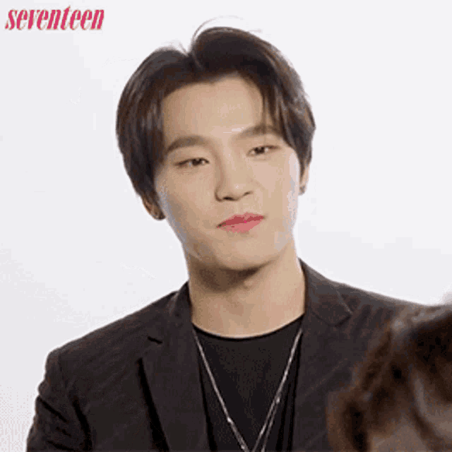 a young man in a suit and a black shirt is looking at a woman .