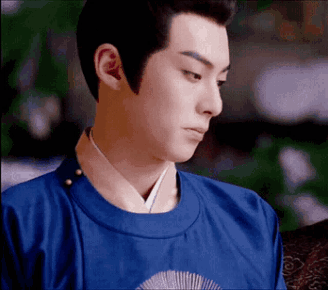 a man in a blue shirt with a fan on his chest looks down