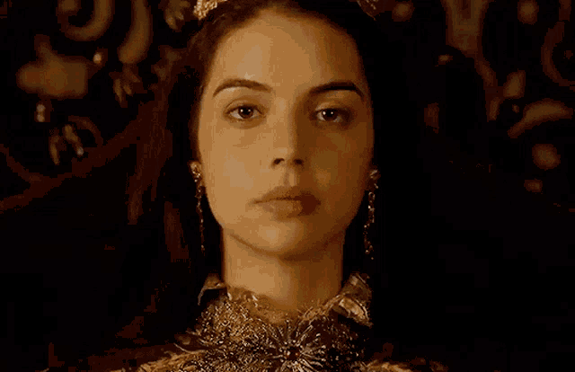 a close up of a woman 's face wearing a tiara and earrings