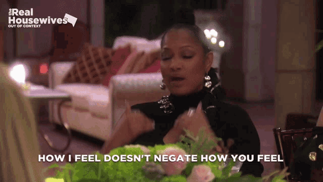 a woman sitting at a table with the words how i feel does n't negate how you feel on the bottom