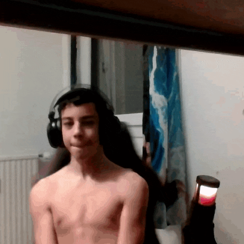 a shirtless young man wearing headphones is looking at the camera