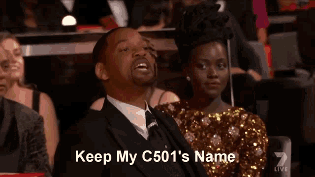 a man in a suit says keep my c501 's name in front of a woman in a sequined dress