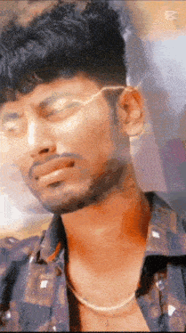 a man with a beard and glasses is wearing a chain around his neck and looking at the camera .