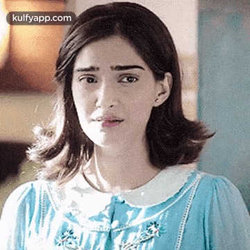 a woman in a blue dress is making a funny face and looking at the camera .