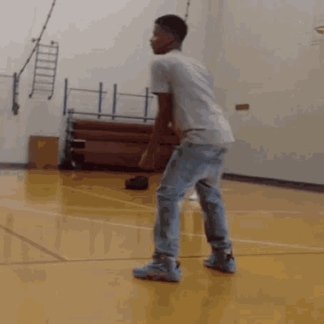 a man is standing on a basketball court in a gym .