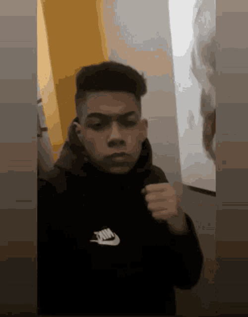 a young man wearing a black nike hoodie is taking a selfie