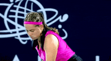 a woman in a pink top and headband is playing tennis on a court .