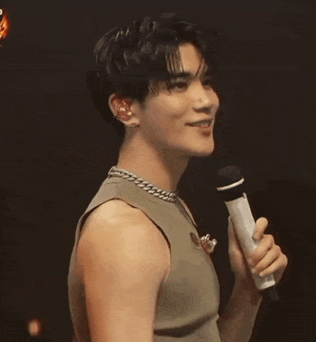 a close up of a man wearing a tank top and a necklace .