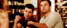 two men are sitting at a table with their arms outstretched .