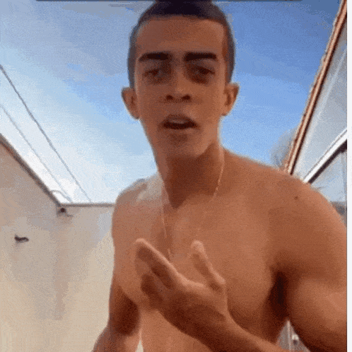 a shirtless man is making a funny face while standing in front of a blue sky .