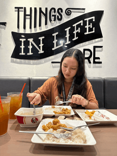 a woman sits at a table with plates of food under a sign that says things in life re