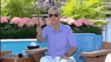 a man in a purple shirt and sunglasses is standing in front of a pool