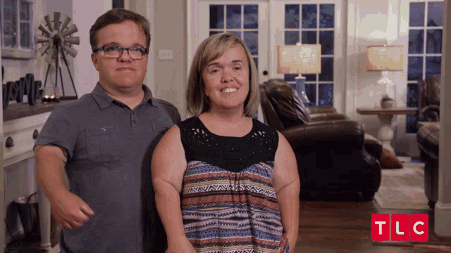 a man and a woman standing in a living room with a tlc logo