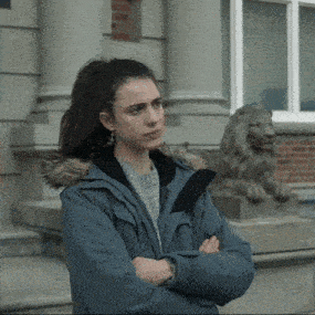 a woman in a blue jacket stands with her arms crossed