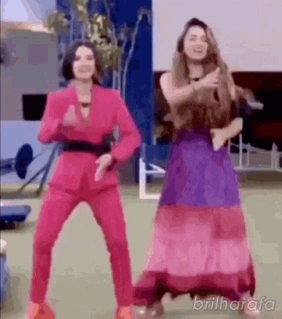 a woman in a pink suit is dancing with a woman in a purple dress .