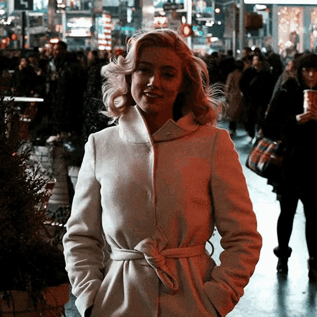 a woman in a white coat is walking down a street