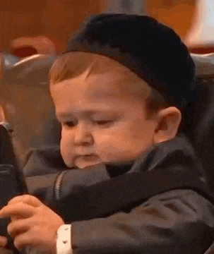 a baby wearing a hat is sitting in a car seat playing with a cell phone .