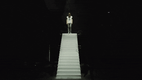 a woman stands on a set of white stairs