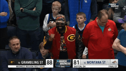 a man in a red jacket with the letter g on it stands in a crowd