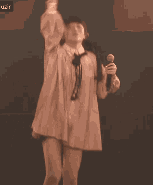 a woman in a pink dress is dancing on stage with a microphone .