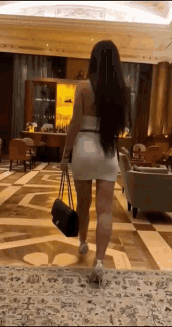 a woman in a short white dress is walking down a hallway