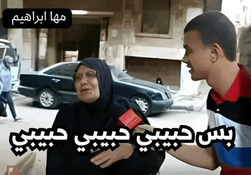 a man is talking to an older woman on a street while a car is parked in the background .