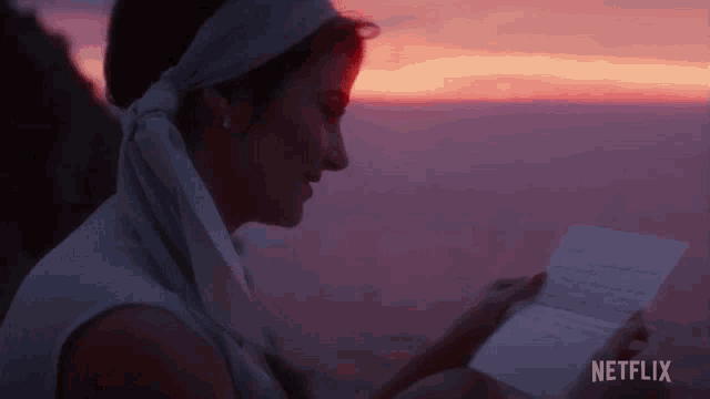 a woman reads a letter from netflix in front of a sunset