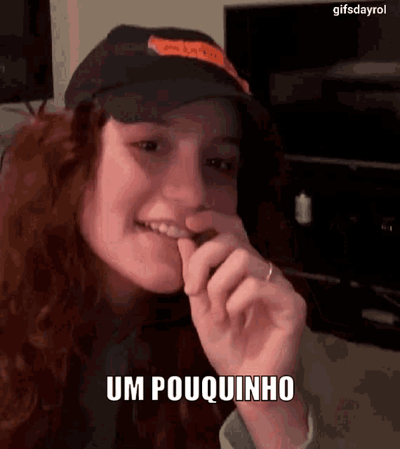 a woman wearing a hat and a ring is eating a piece of chocolate .