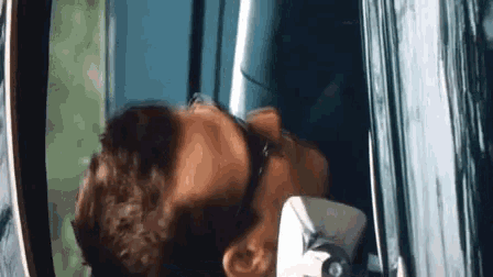 a man wearing sunglasses is leaning out of a window .