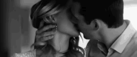 a black and white photo of a man and woman kissing each other .