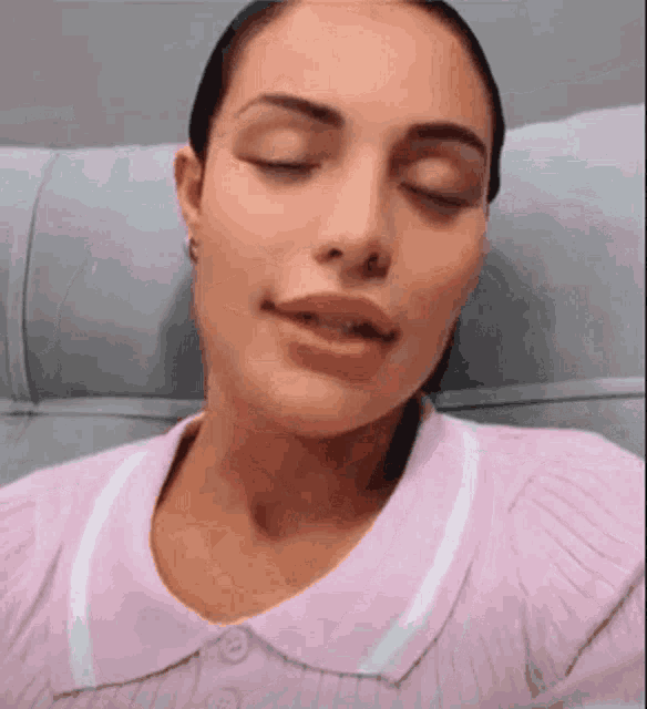 a woman is sitting on a couch with her eyes closed and smiling .