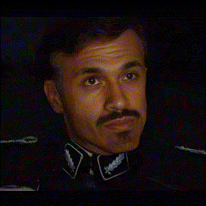 a man in a military uniform with a mustache is looking at the camera in a dark room .