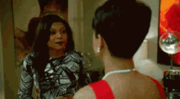 a woman in a red dress is talking to another woman in a room .