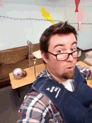 a man wearing glasses and a vest that says " the hungry birds "