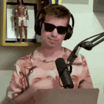 a man wearing headphones and sunglasses is talking into a microphone .