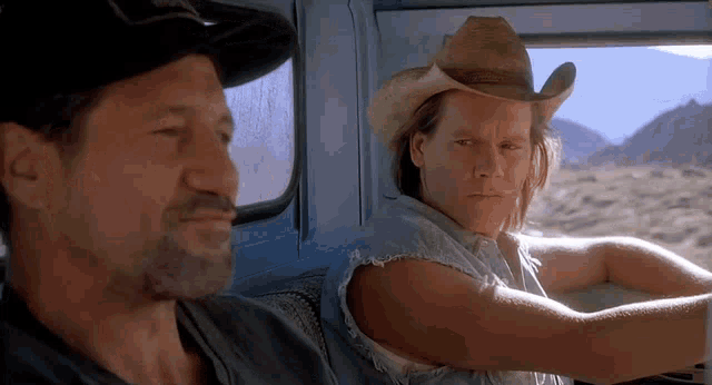 two men in cowboy hats are sitting in a truck