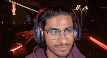 a man wearing headphones and glasses is looking at the camera .