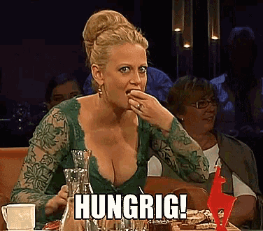 a woman is sitting at a table with her mouth open and the word hungrig written on her face