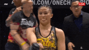 a woman wearing a shirt that says ' fighter ' on it stands in front of a sign that says one